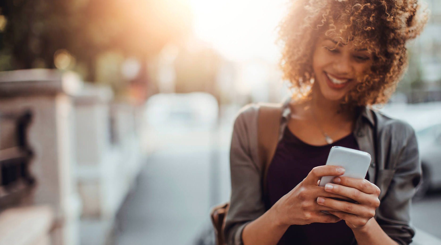 a woman walking outside with her cell phone