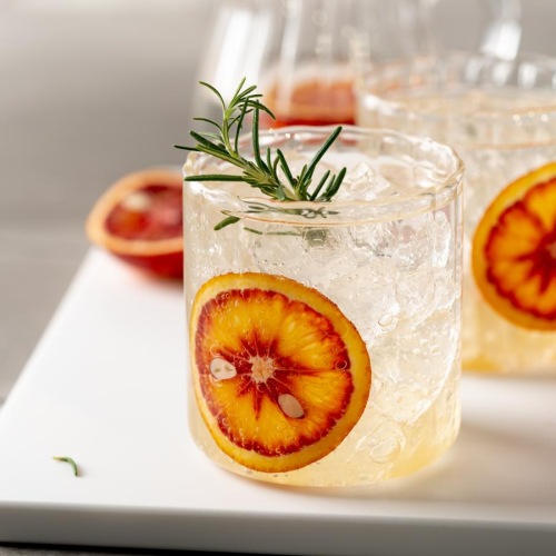 a glass of liquid with fruit and a slice of strawberry on a plate